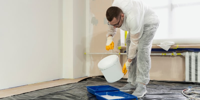 Worker preparing moisture-resistant wall paint with primer in a Dubai apartment – Dubai moisture resistant wall paints