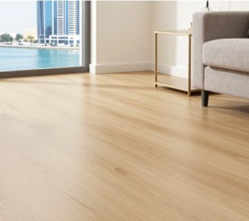 A bright Dubai living room with SPC wood-look flooring, beige sofa, and Marina skyline view—emphasizing waterproof performance and aesthetic appeal in the best flooring for Dubai apartments.