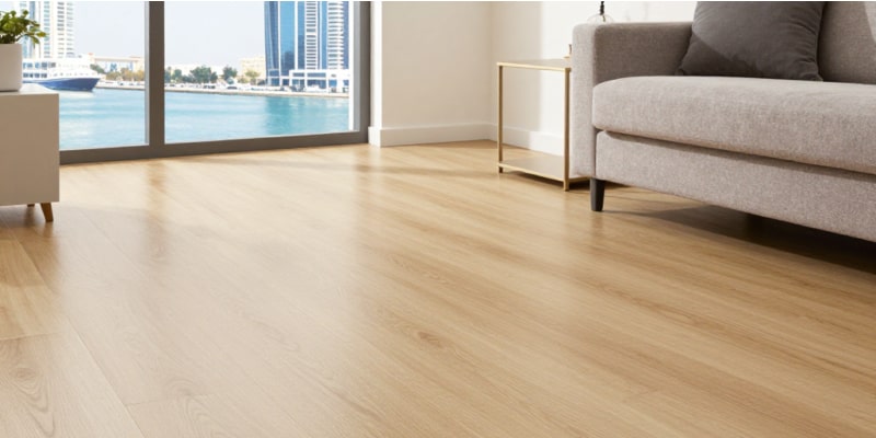 A bright Dubai living room with SPC wood-look flooring, beige sofa, and Marina skyline view—emphasizing waterproof performance and aesthetic appeal in the best flooring for Dubai apartments.