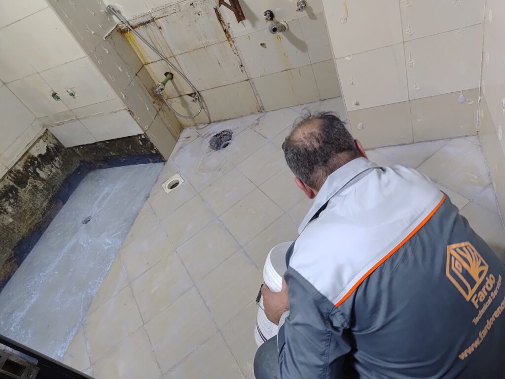 A professional technician from Fardo Technical Services waterproofing and repairing a bathroom floor during a renovation project.