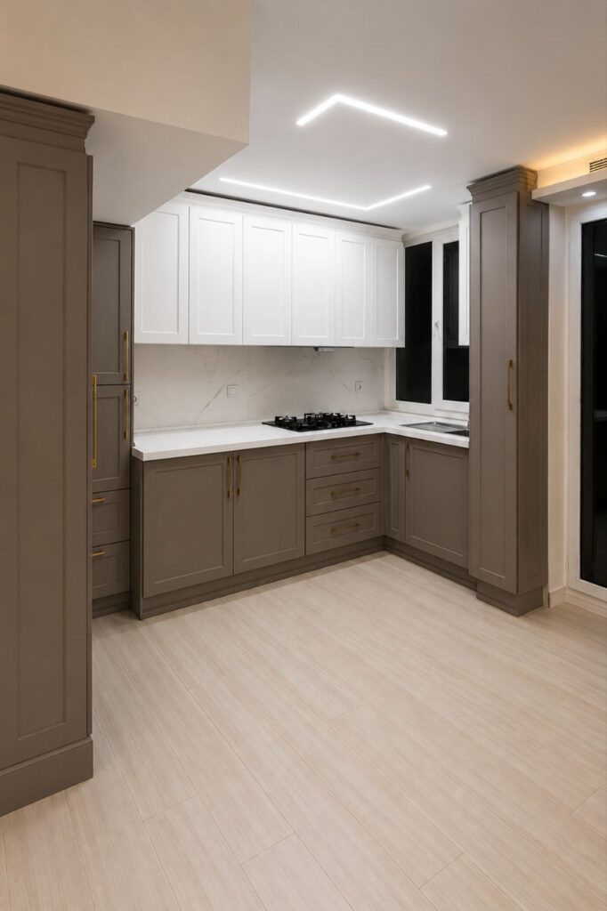 A modern neo-classical kitchen by Fardo Technical Services with two-tone grey and white shaker cabinets, gold handles, and linear LED ceiling lighting.